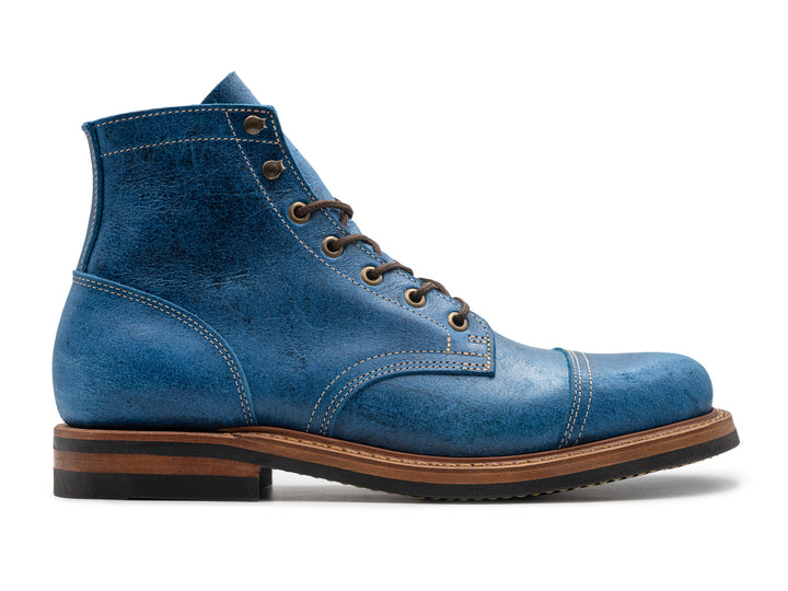 side view of blue textured leather boot on white background