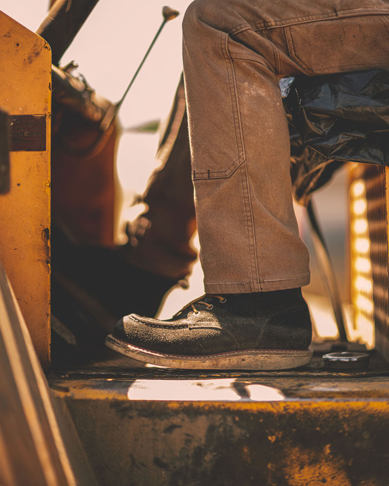 man sitting in tractor showing canvas work pants and black rough out boots