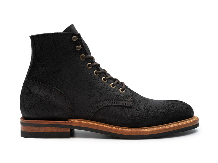 side view of black oiled rough out leather boot on white background