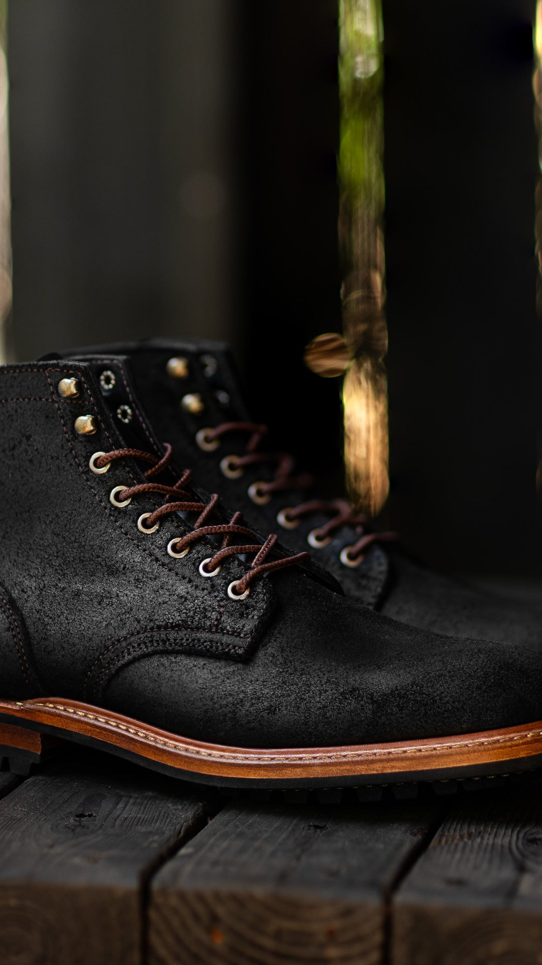 black textured boot on black wood with out of focus streaky background