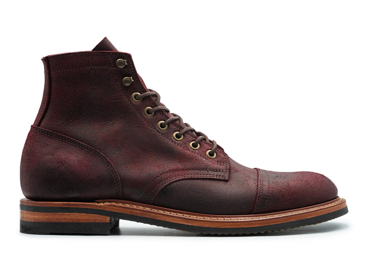 side view of dark burgundy leather boot on white background