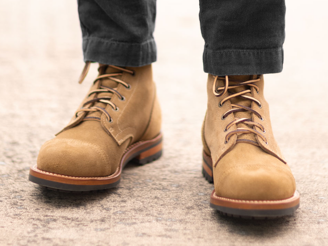 tan boots worn with black pants outside on cement