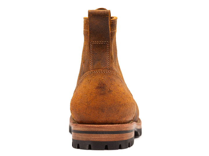 back view of brown orange textured leather boot on white background