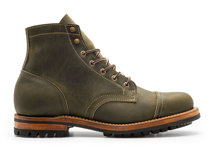side view of rugged green leather boot on white background
