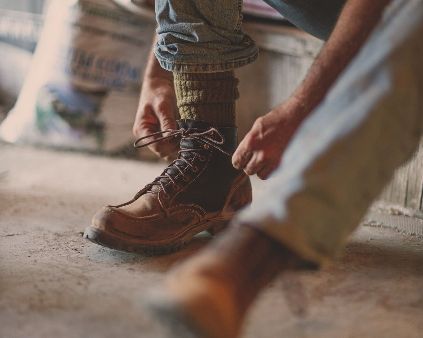 man tying laces on brown leather boots