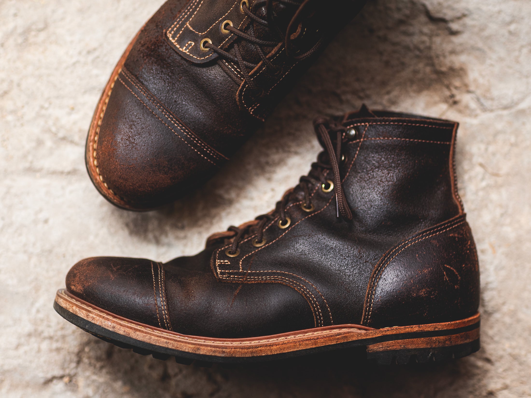 pair of distressed brown leather boots on stone background