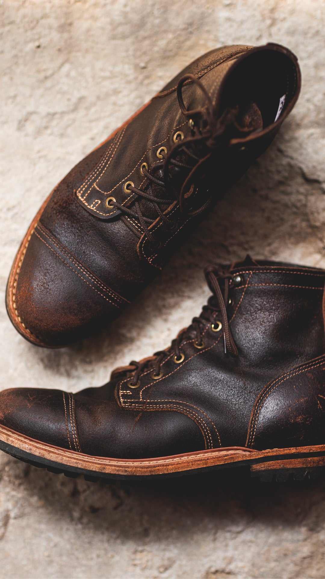 pair of distressed brown leather boots on stone background