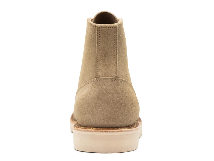 Tan boot with a white sole on a white background back view