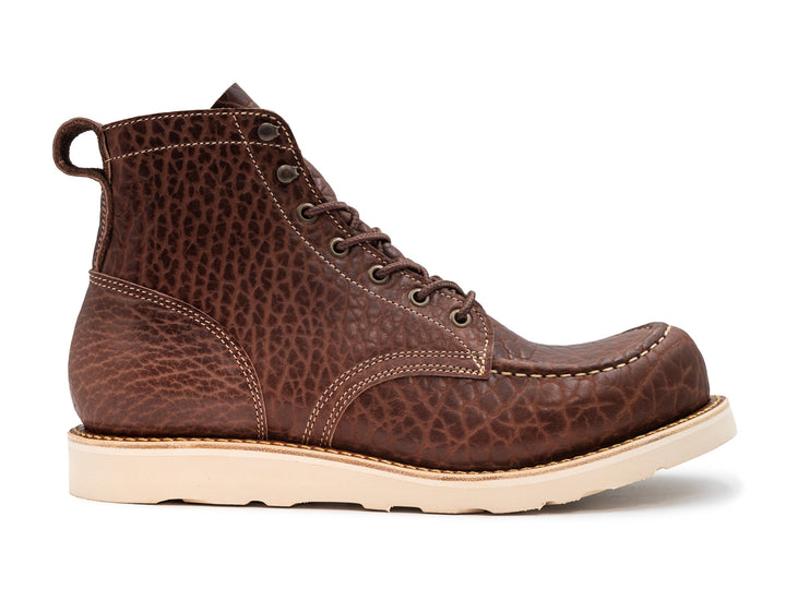 side view of brown textured leather boot with wedge sole on white background