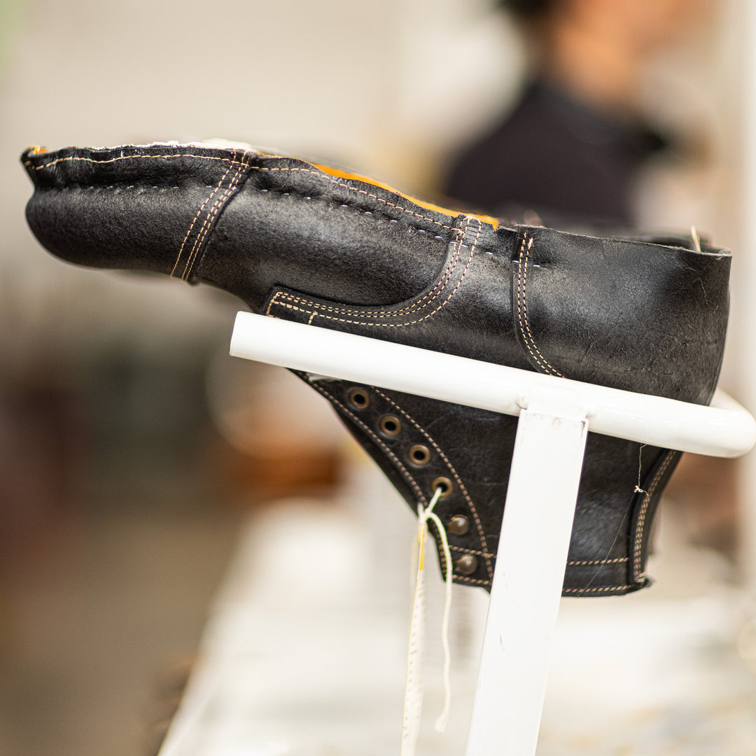 individual gray textured leather boot in production upside down on rack