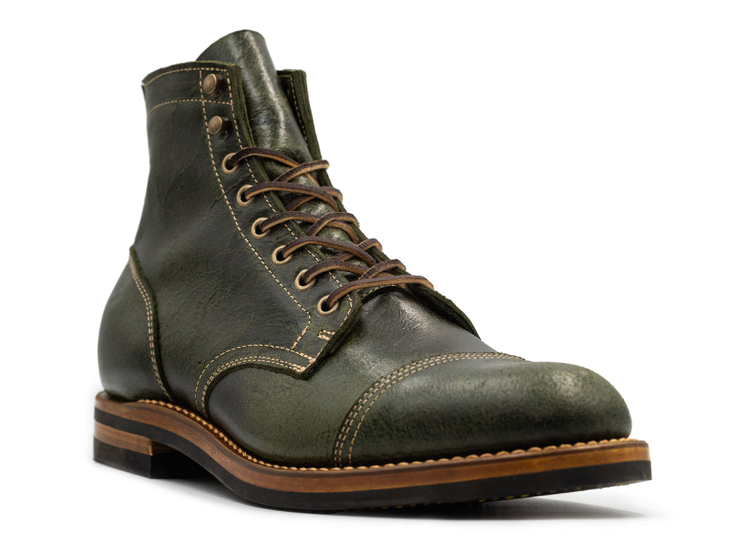 three-quarter view of a textured green leather boot on white background