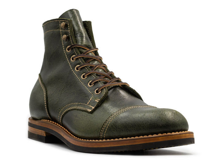 three-quarter view of a textured green leather boot on white background