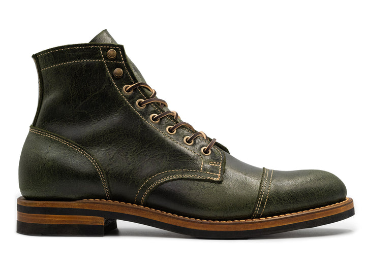 side view of a textured green leather boot on white background