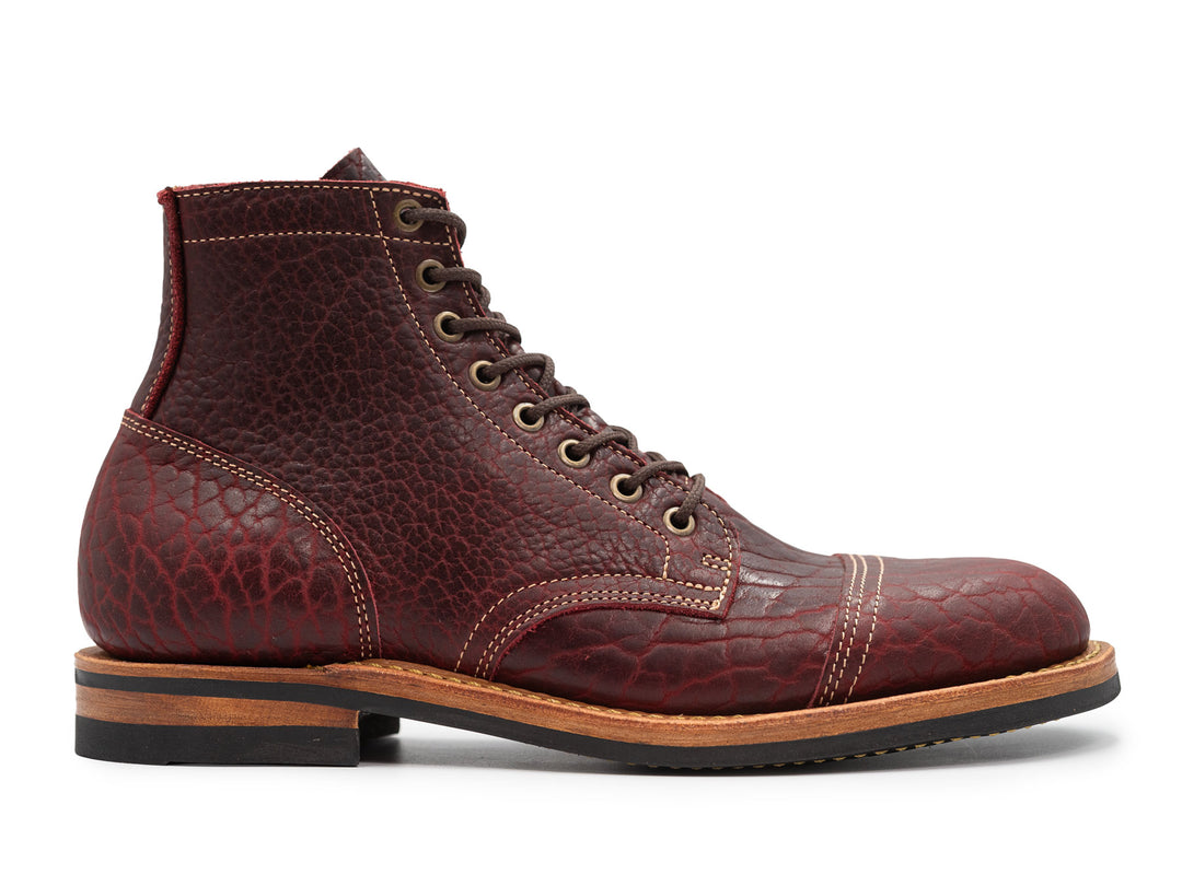 side view of textured burgundy bison leather boot on white background