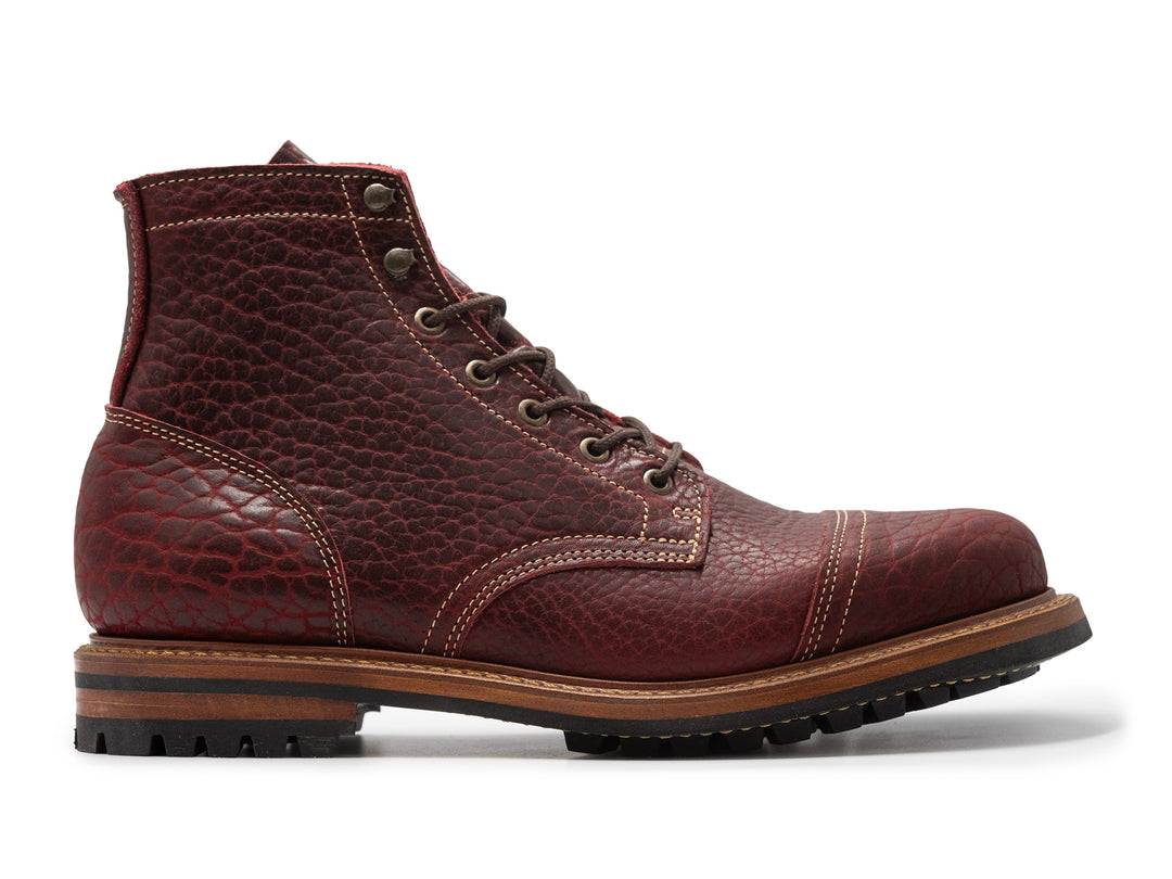 side view of textured burgundy bison leather boot on white background