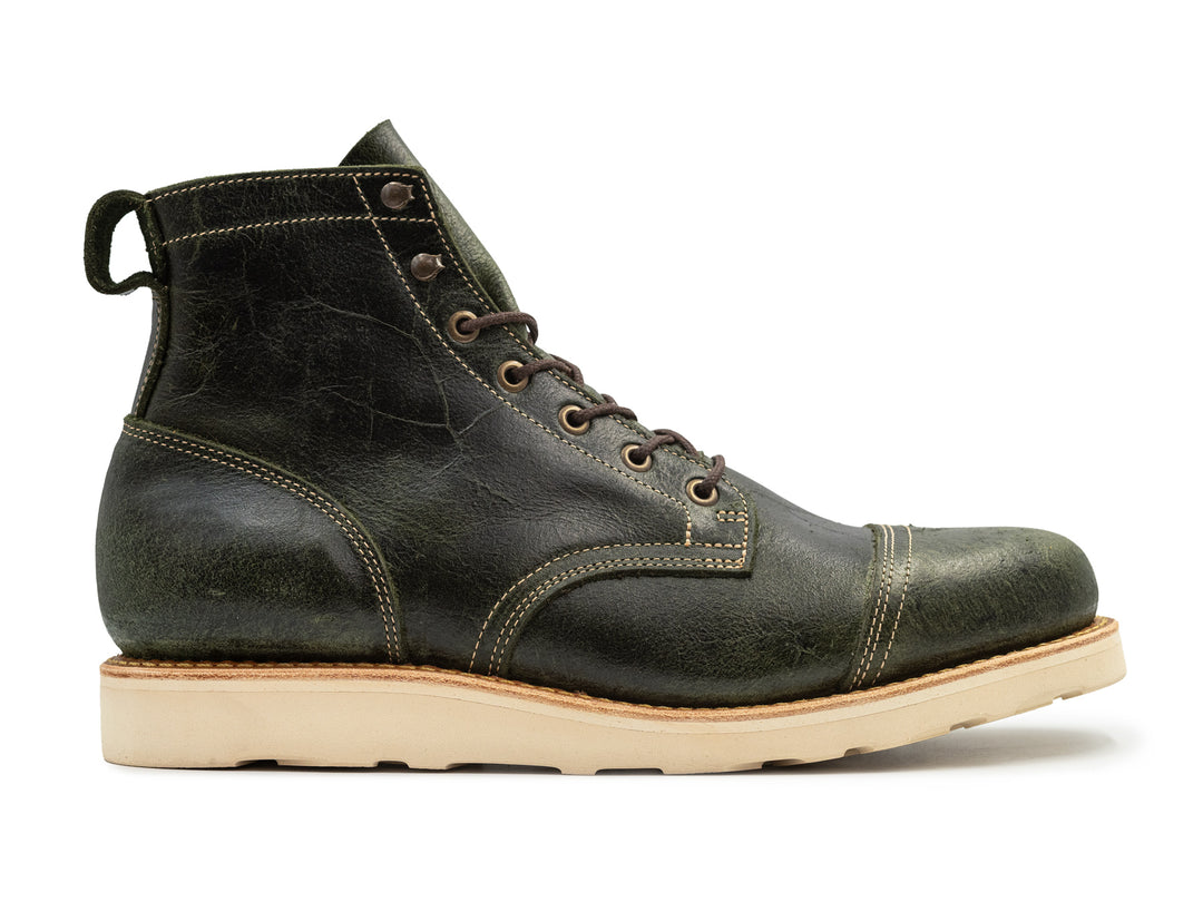 side view textured green leather boot on white background