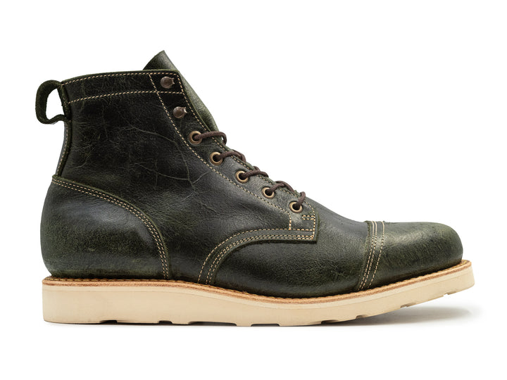 side view textured green leather boot on white background