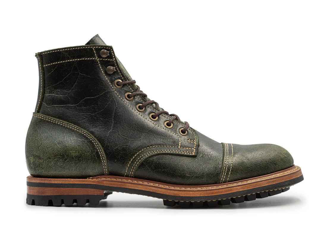 side view of textured green leather boot on white background