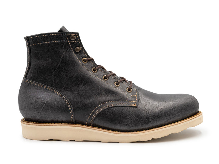 side view of textured gray leather boot with white wedge sole on white background