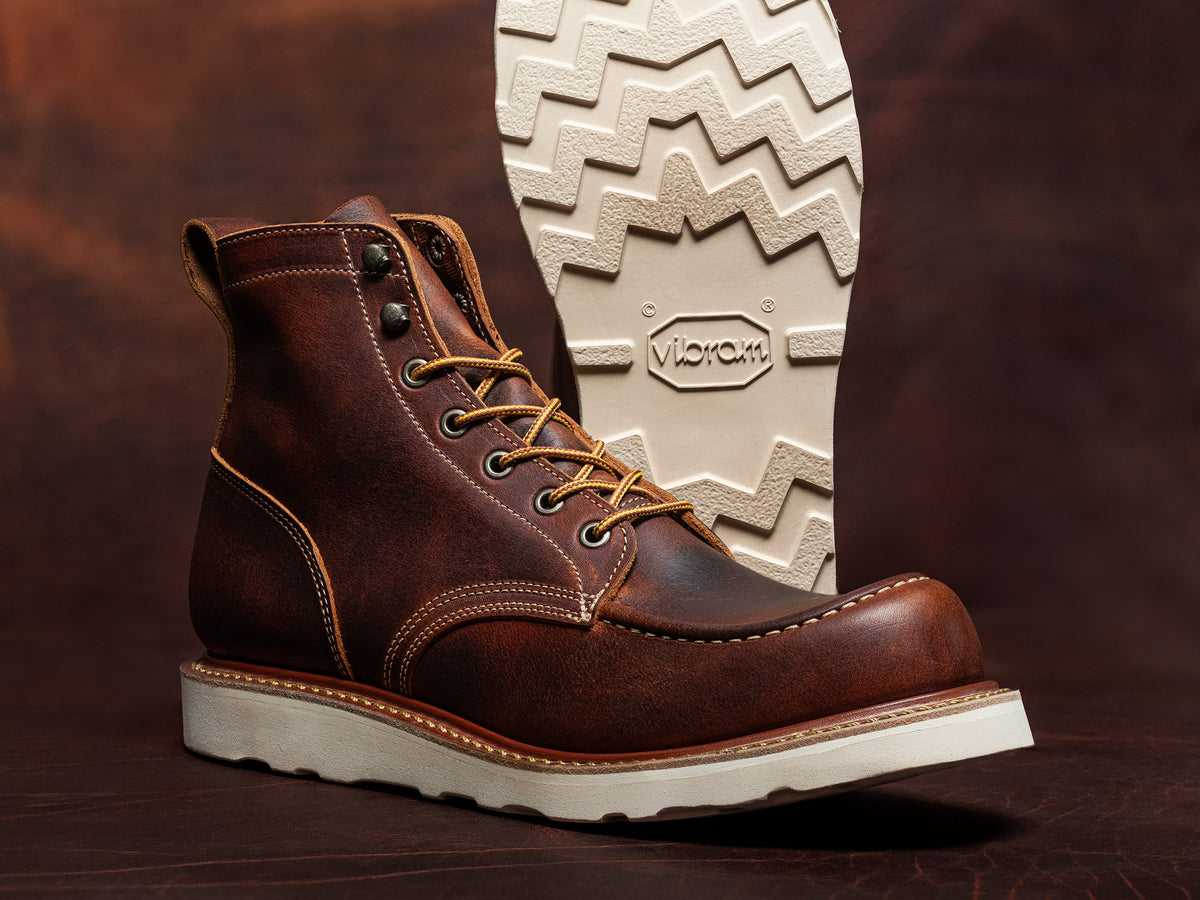 rustic tobacco snakebite leather moc toe boots on brown leather backdrop