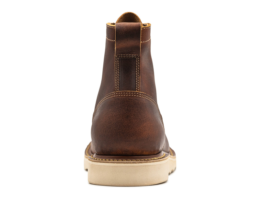 rear view of rustic brown leather moc toe boot on white background