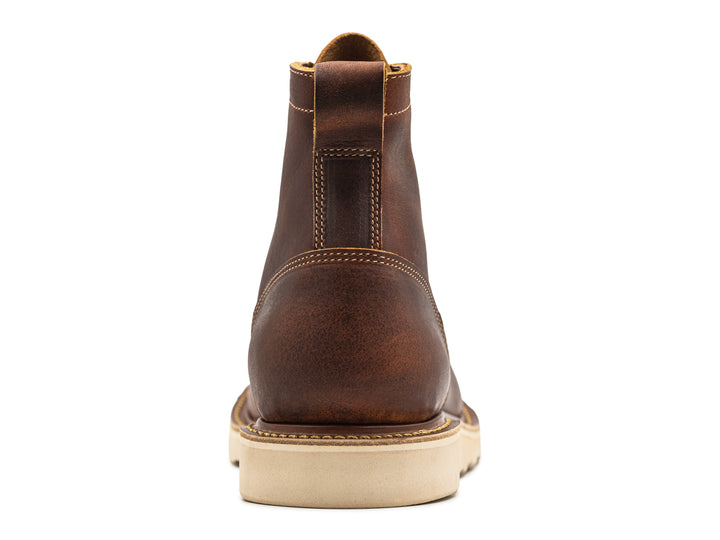 rear view of rustic brown leather moc toe boot on white background