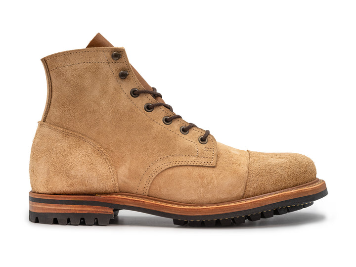 side view of tan rough out leather boot on white background