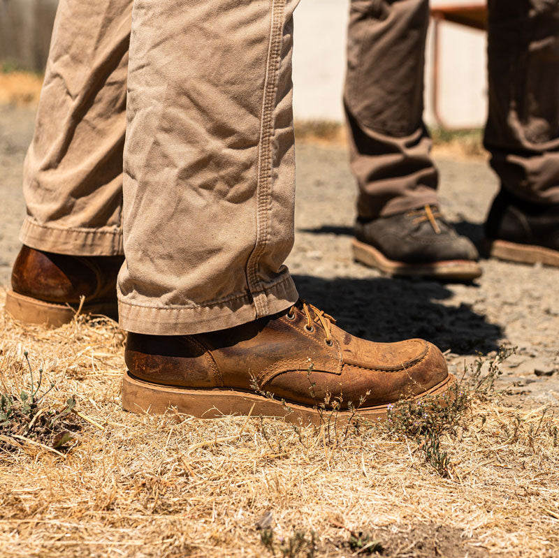 man standing outside in khaki pants and worn in brown leather boots